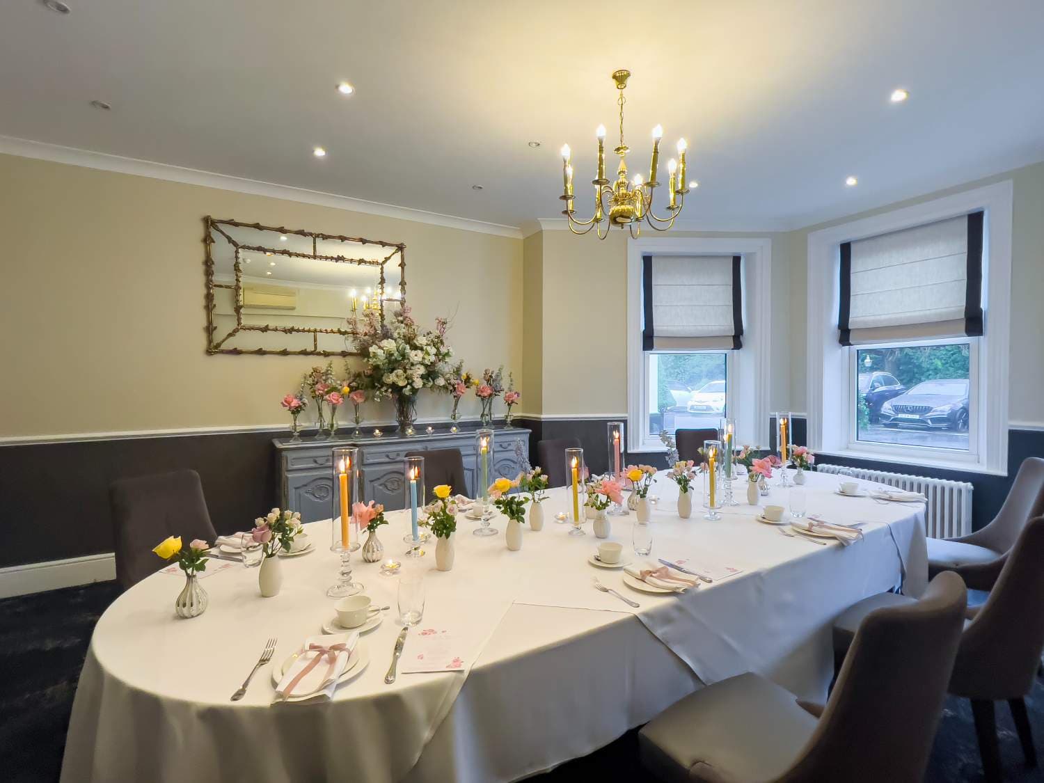 Private dining room at The Spa Hotel with oval table set for a formal occasion with candles and flowers.