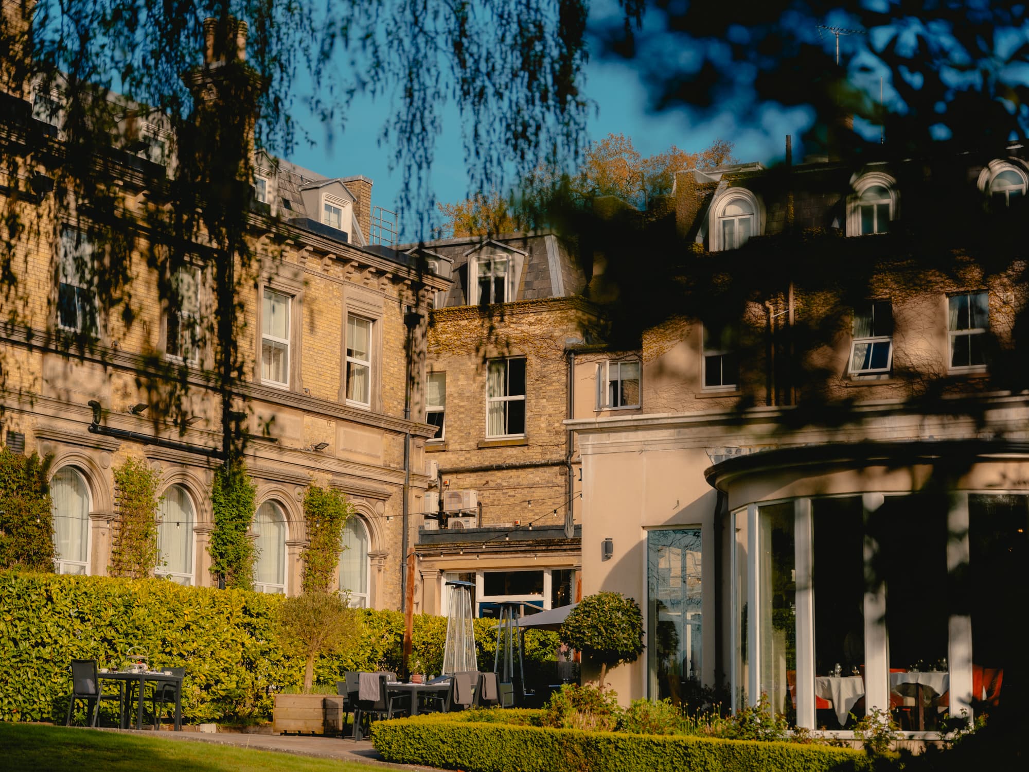 The Spa Hotel exterior with garden terrace, outdoor seating and Victorian stone facade.