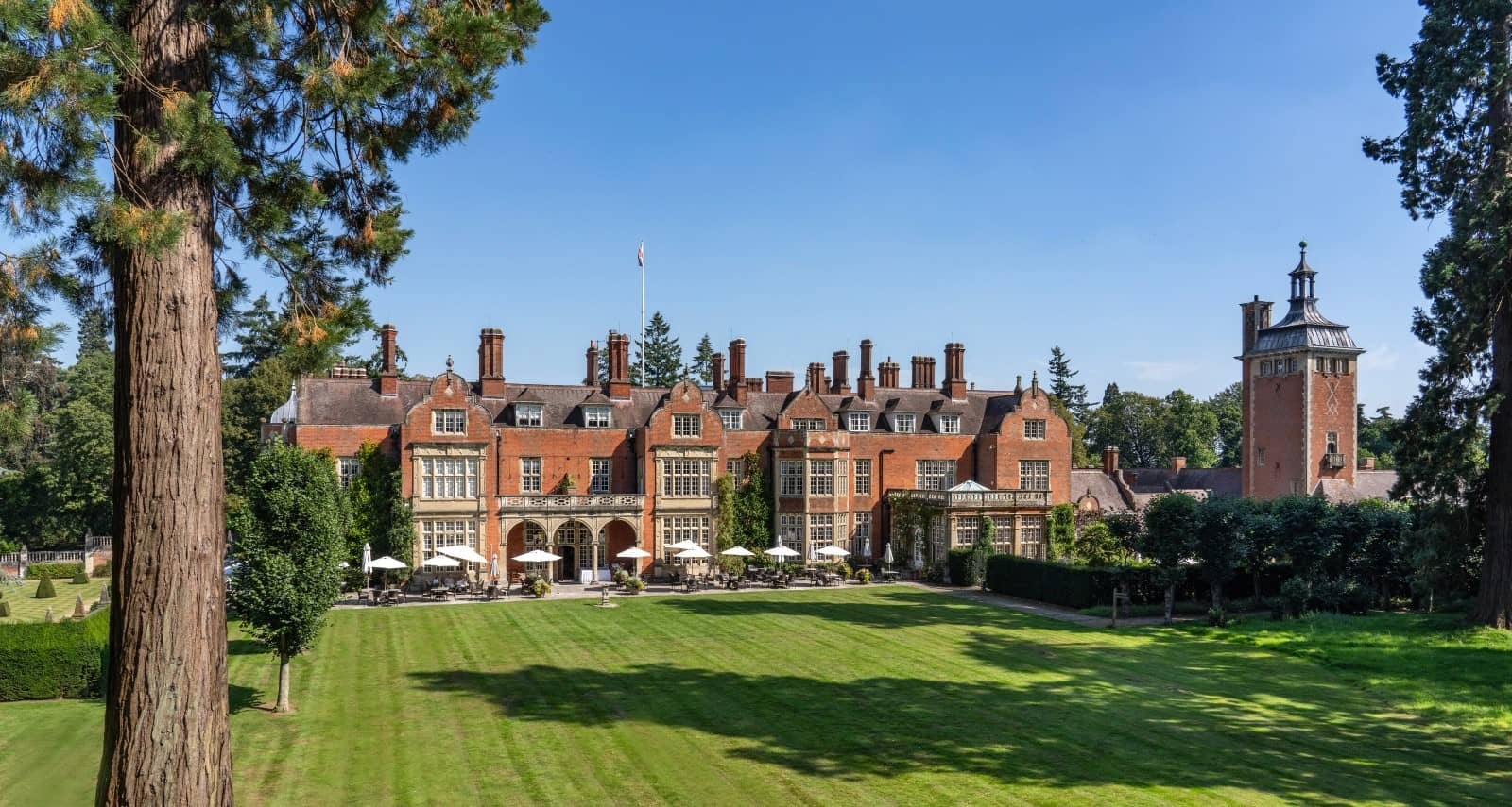 The red brick exterior and manicured lawns of Tylney Hall Hotel on a sunny day.