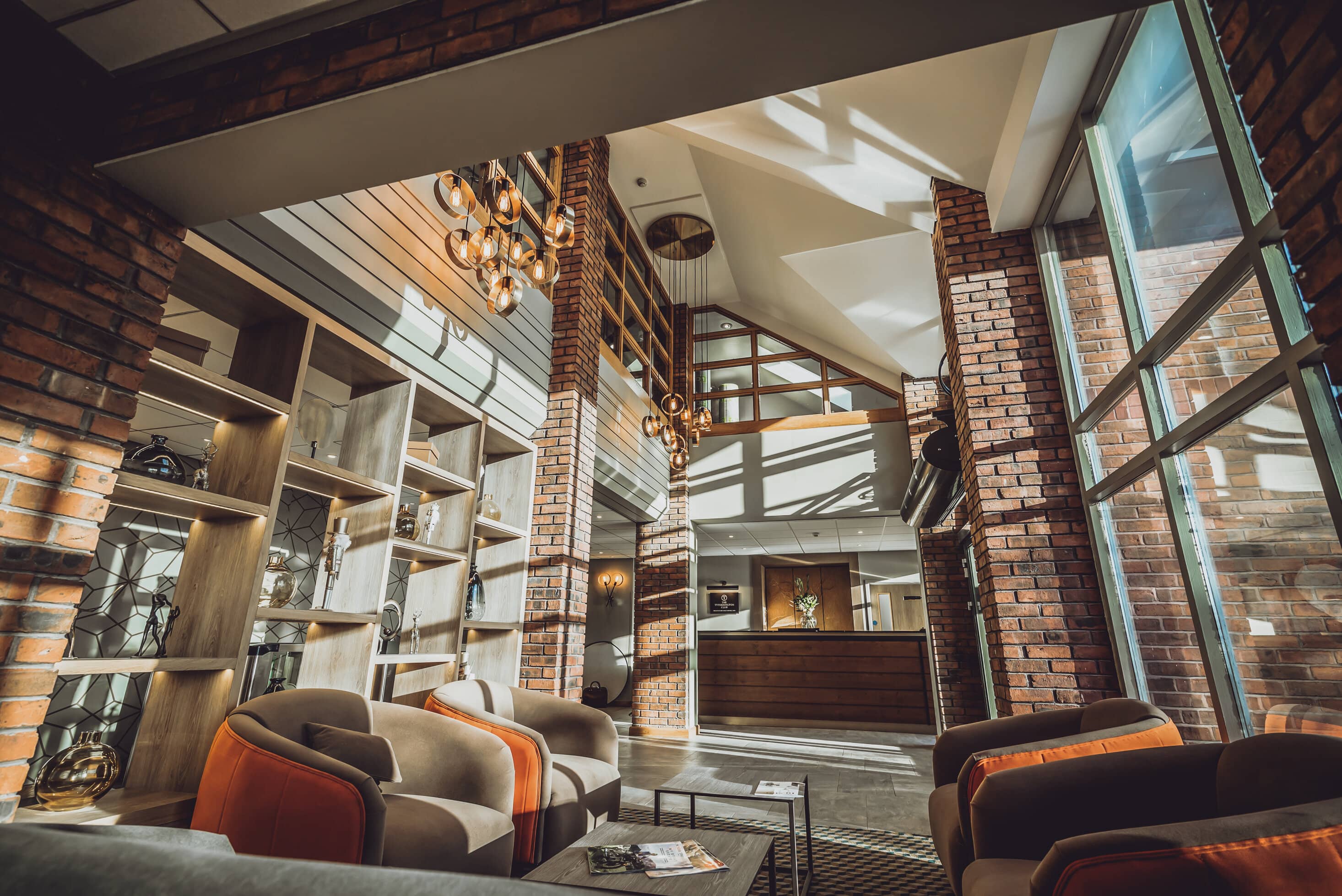 Hotel lobby at Tytherington Club with exposed brick columns, pendant lighting and seating area.