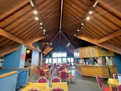 Interior of a golf club bar and dining area with a vaulted timber ceiling.